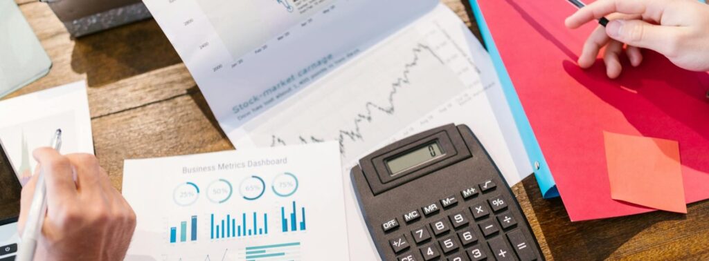 Zwei Personen analysieren Finanzdiagramme und verwenden einen Taschenrechner. Das Bild wird für den Abschnitt über Geschäftsideen mit Zukunft verwendet.